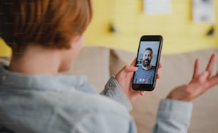 Giovane donna a casa che fa una videochiamata usando lo smartphone, concetto di social network.