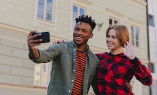 Young mixed couple making selfie for soial networks outdoors in a town.