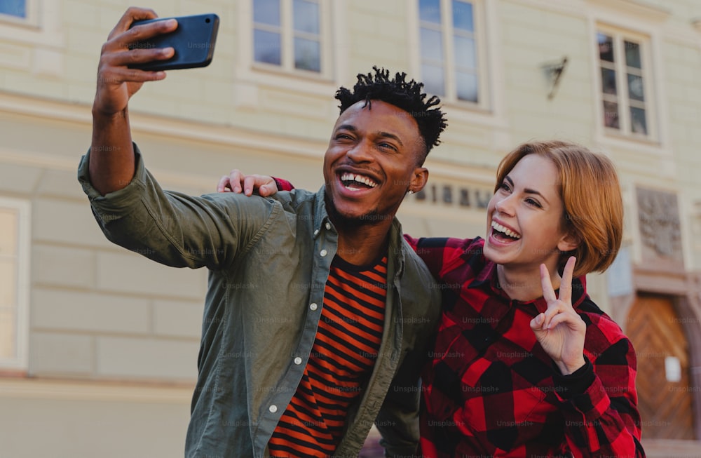 Young biracial couple making selfie for soial networks outdoors in a town.