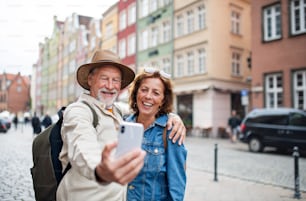 Un ritratto di turisti di coppia anziana felici che fanno selfie all'aperto nella città storica