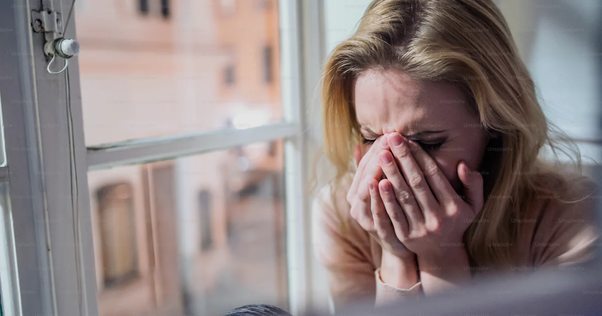 Window Cry Beautiful blond woman sitting on window sill at night, looking out of ...