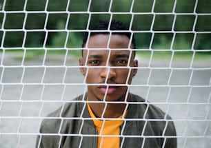 Frustrierter junger schwarzer Mann hinter dem Netz draußen in der Stadt.