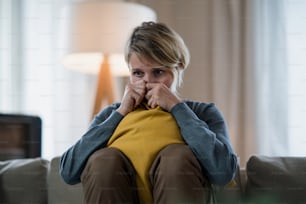 Mujer preocupada con tableta en el interior en el sofá de casa sintiéndose estresada, concepto de salud mental.