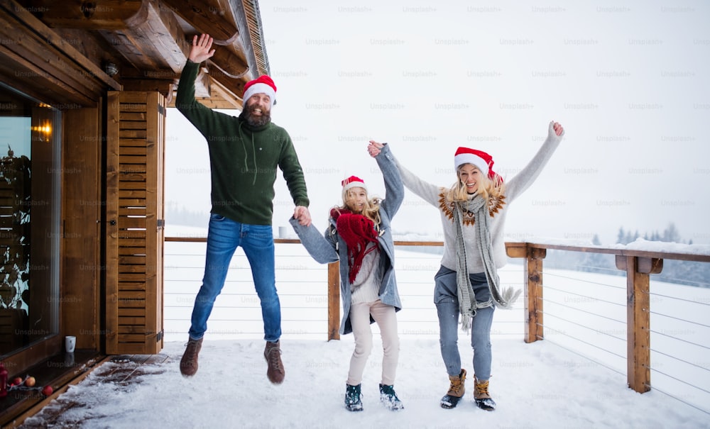 Familie mit einer kleinen Tochter, die Spaß auf der Terrasse im Freien hat, Urlaub in der Weihnachtszeit.