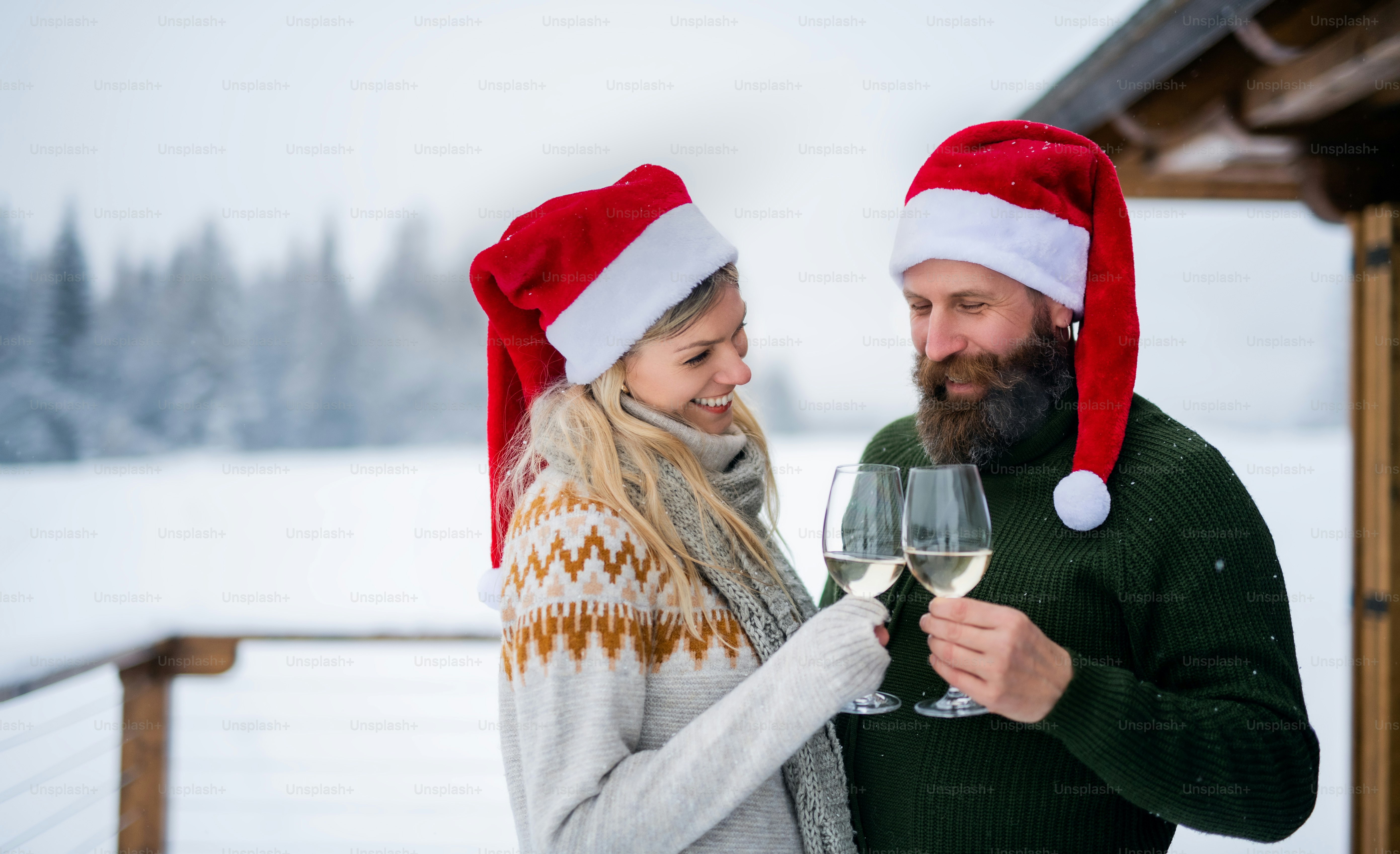 Happy mature couple drinking wine on terrace outdoors in winter nature, holiday at Christmas time