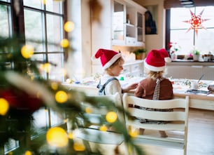 Rückansicht eines gl�ücklichen kleinen Mädchens und Jungen zu Weihnachten drinnen zu Hause, Bilder malen.