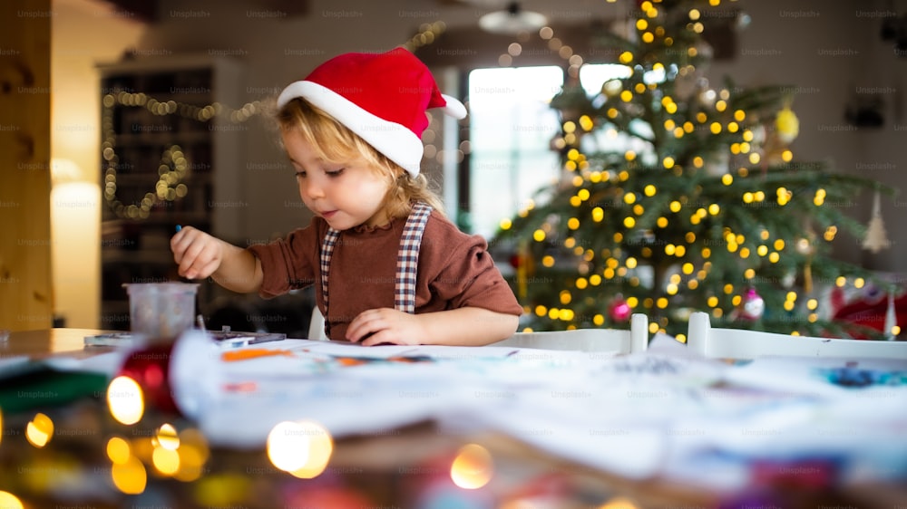Ritratto di bambina felice in casa a Natale, dipingere quadri.