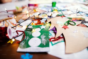 Children's paintings and Christmas paper art and craft indoors on table.