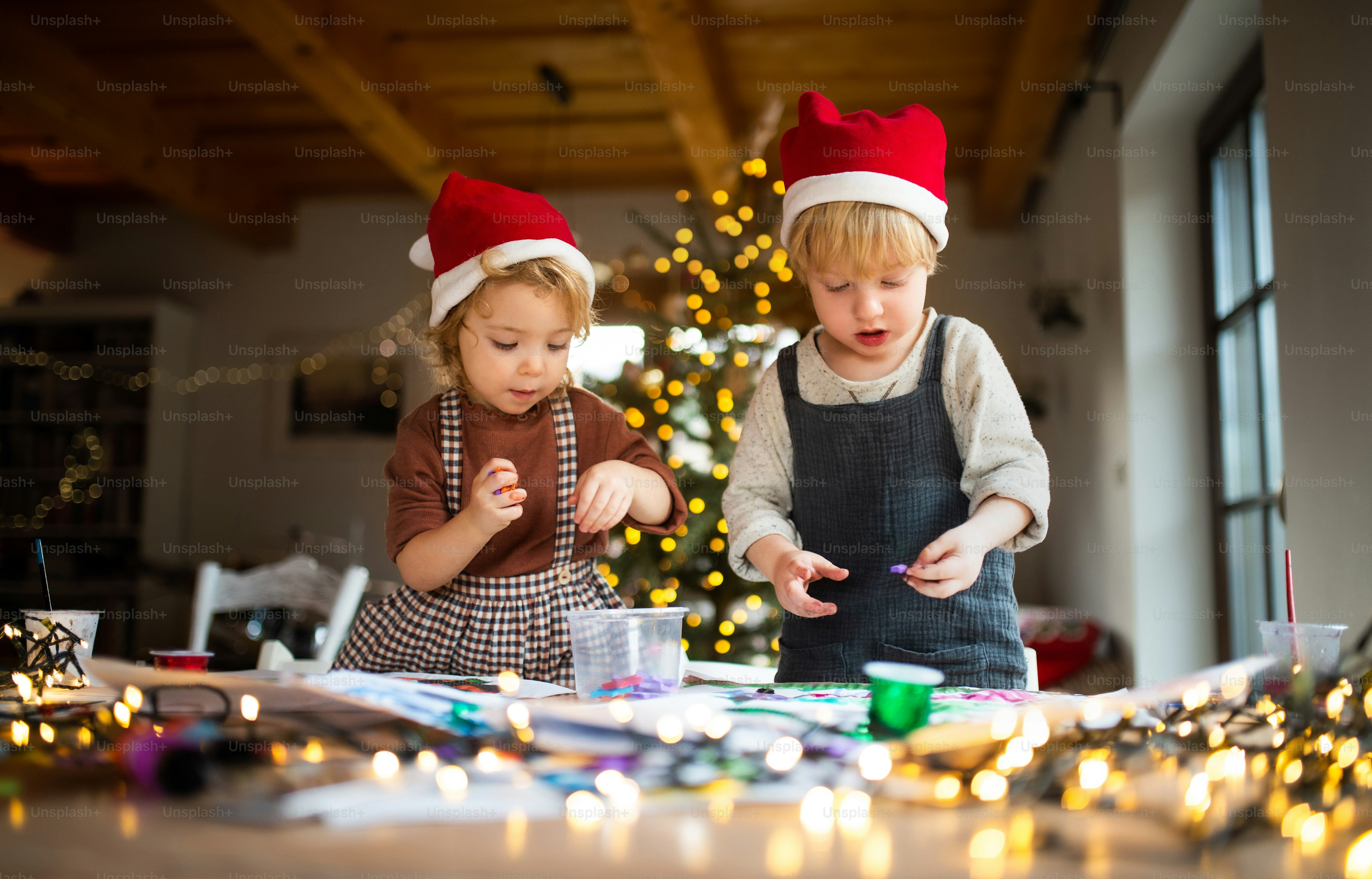 Retrato de niña y niño felices en el interior de su casa en Navidad, haciendo arte y manualidades.