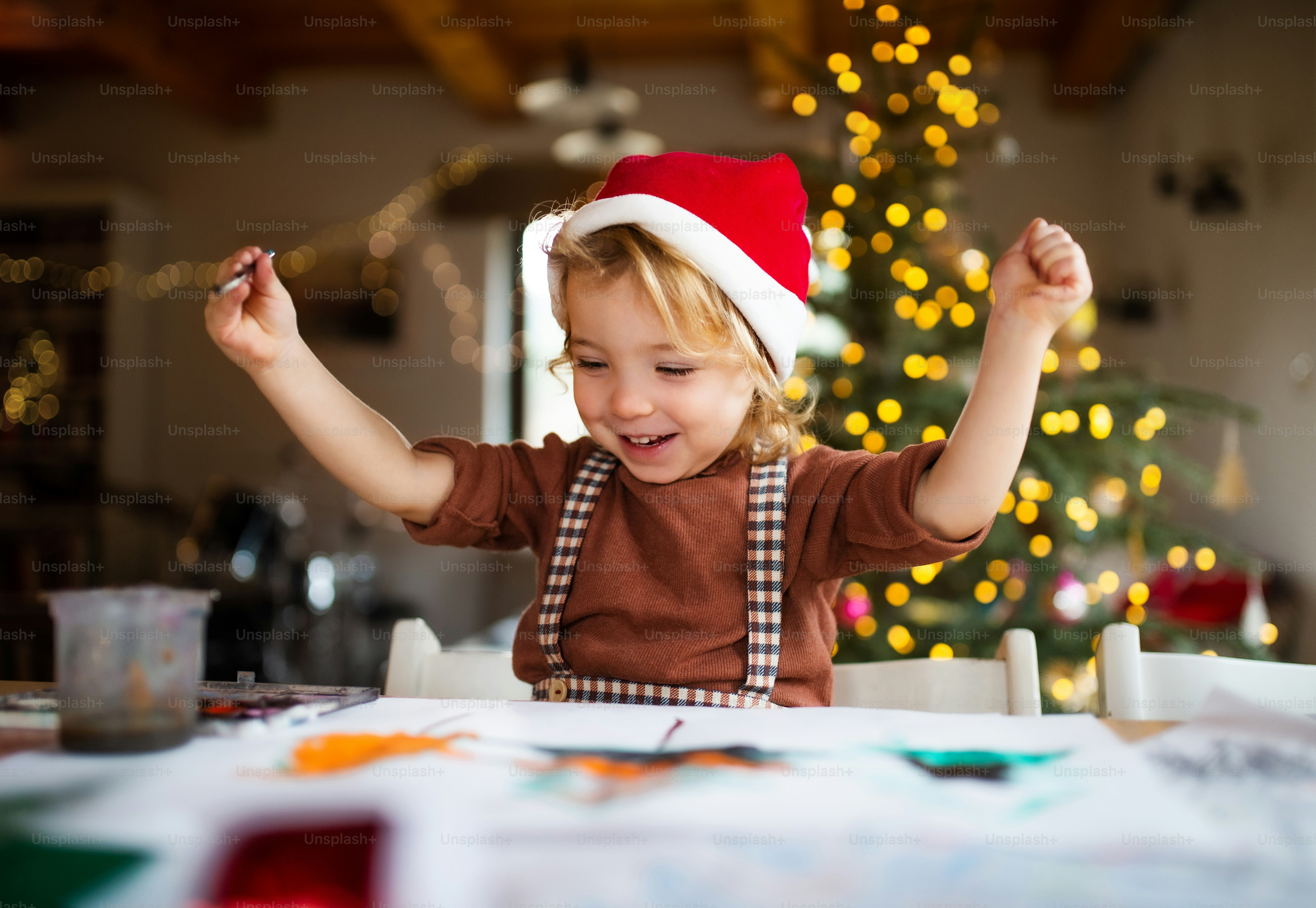 Porträt eines glücklichen kleinen Mädchens, das zu Weihnachten zu Hause ist und Bilder malt.