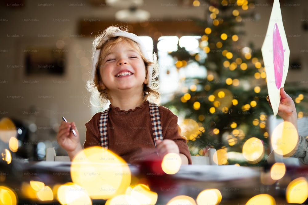 Ritratto di bambina felice in casa a Natale, ridendo.