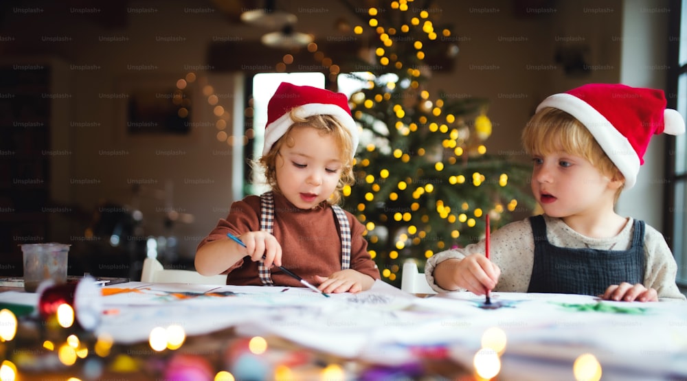 Ritratto di bambina e ragazzo felici in casa a Natale, dipingere immagini.