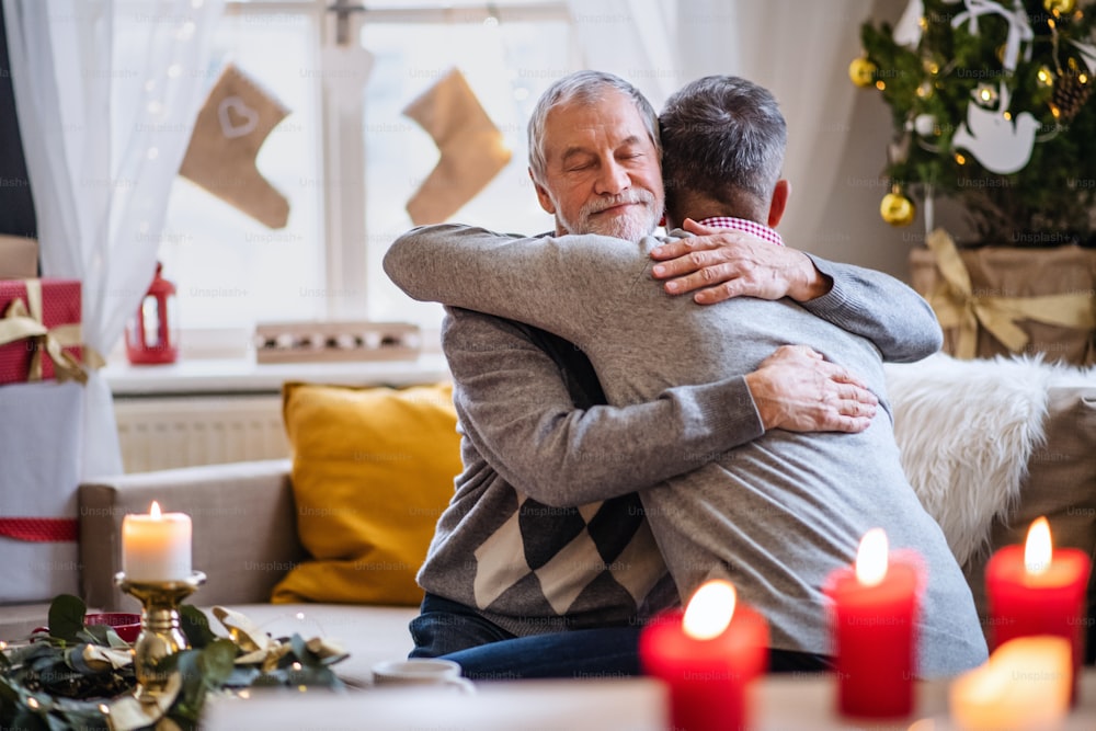 행복한 성숙한 남자와 노인 아버지는 크리스마스에 집에서 실내에서 포옹합니다.