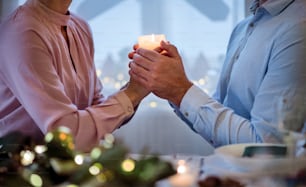 Midsection of unrecognizable couple indoors at the table celebrating Christmas.