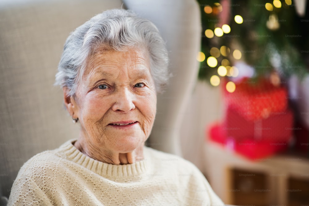 Ein Porträt einer einsamen Seniorin im Rollstuhl zu Hause zur Weihnachtszeit.