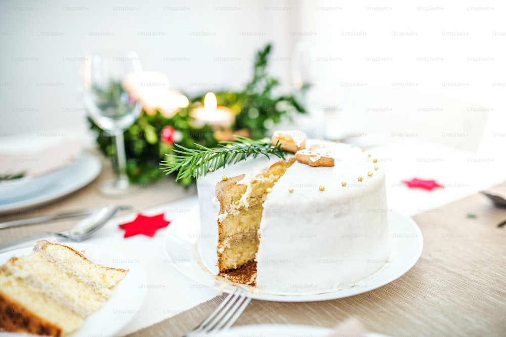 A white a cake on table set for dinner at Christmas time.