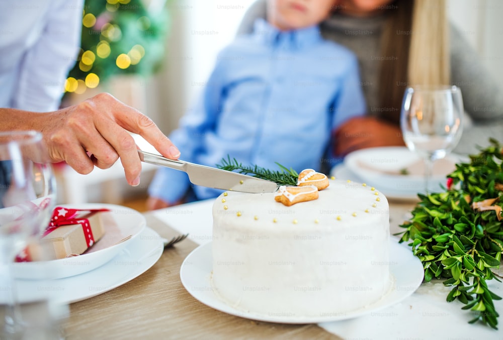 Mujer irreconocible con familia cortando un pastel en Navidad.