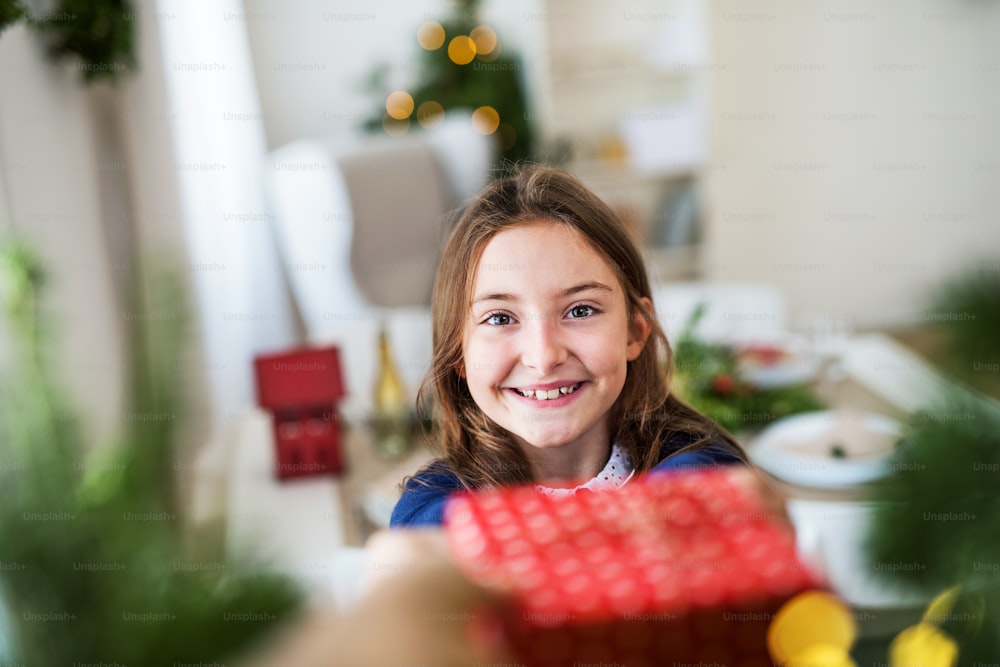 Una bambina felice con un regalo a casa nel periodo natalizio.