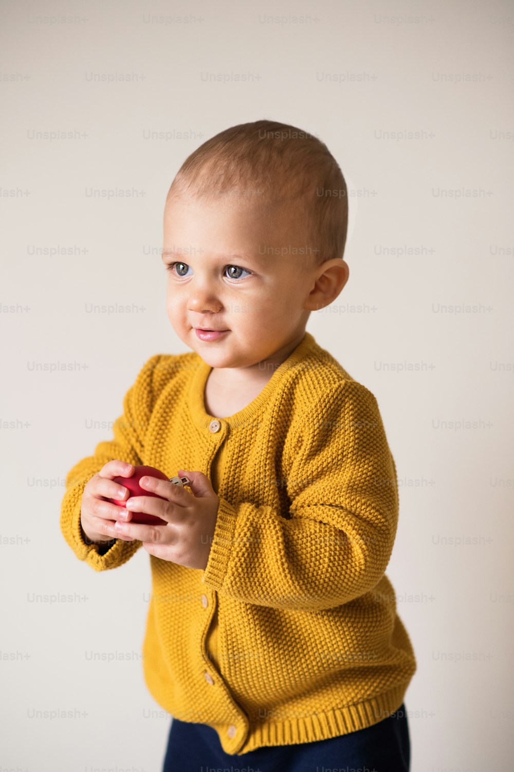 Portrait of a cute toddler boy holding a red ball. Christmas time.