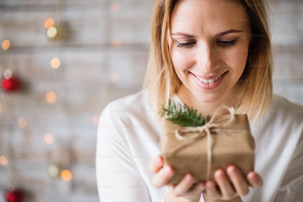 Beautiful young woman holding wrapped Christmas present.