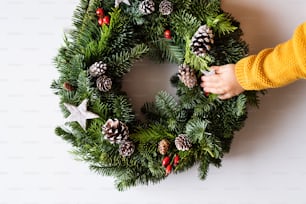 Christmas wreath on a white background. Toddler hand touching a star.