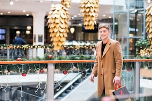 クリスマスにショッピングセンターを歩く10代の少年のポートレート。スペースをコピーします。