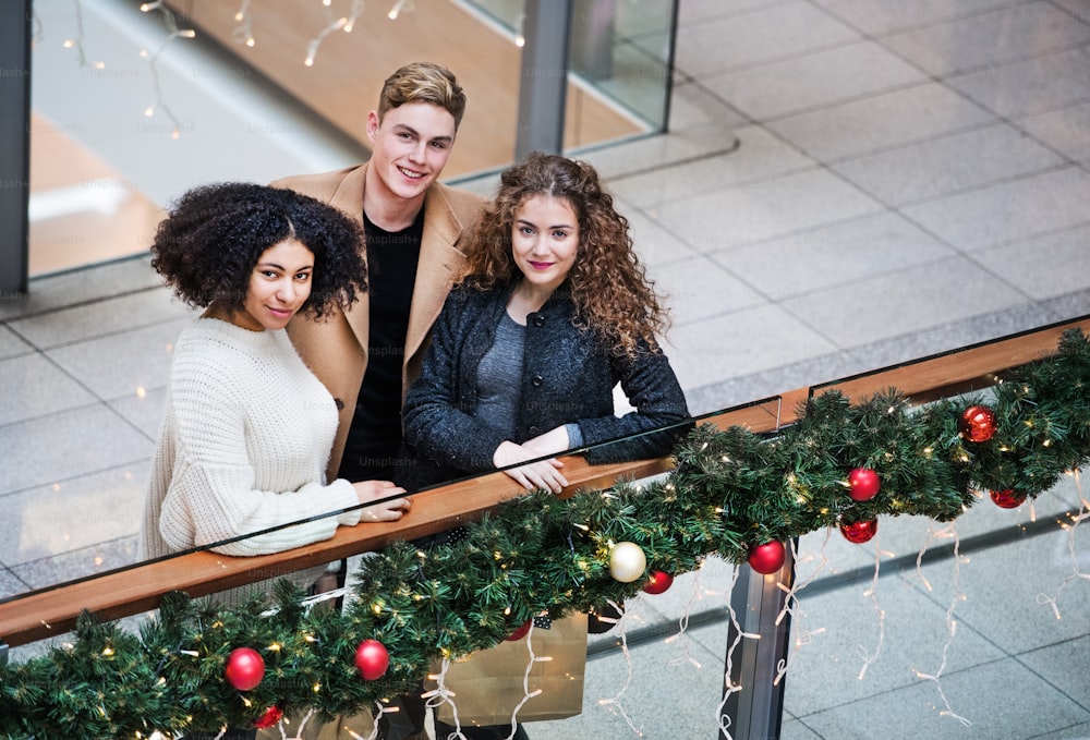 High-angle view of young friends standing in shopping center at Christmas time.