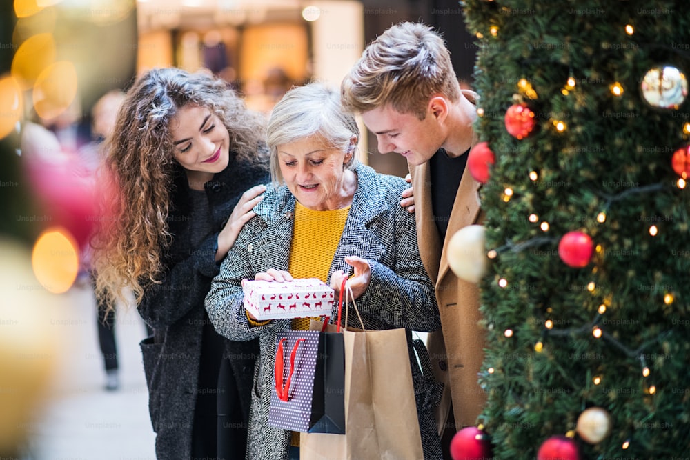 A young couple giving a present to grandmother in shopping center at Christmas time.
