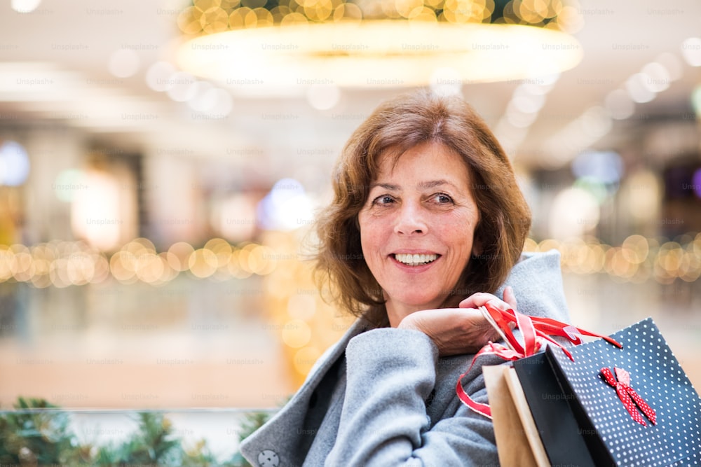 Mulher idosa fazendo compras de Natal. Shopping center na época do Natal.
