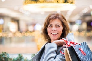 Senior woman doing Christmas shopping. Shopping center at Christmas time.