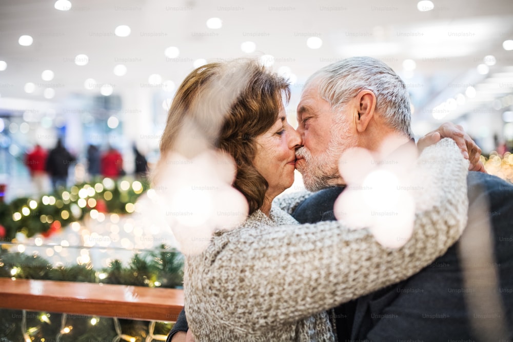 Eine Nahaufnahme eines glücklichen älteren Paares, das im Einkaufszentrum steht und sich küsst.