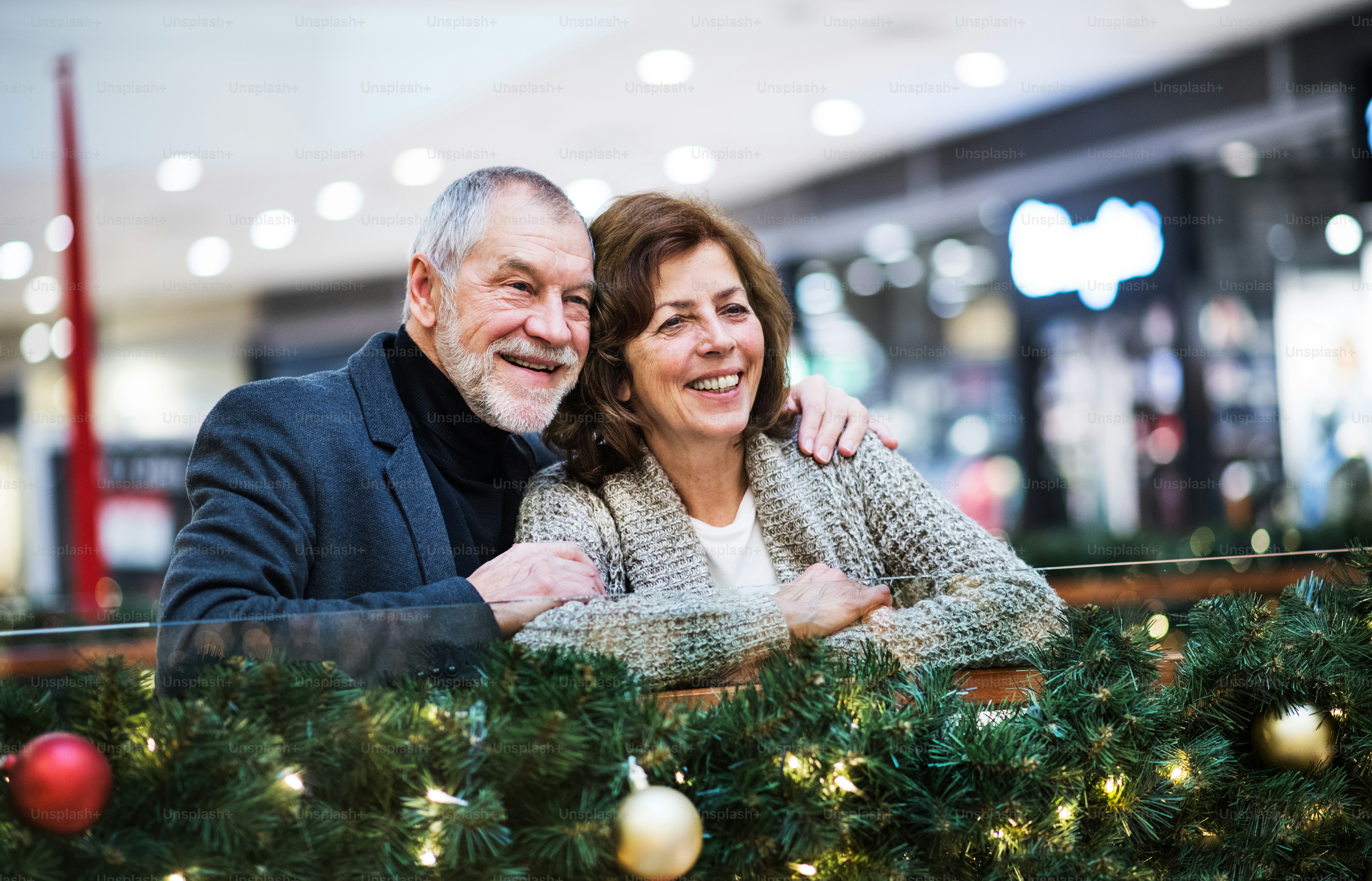 Un portrait d’un couple de personnes âgées heureux dans un centre commercial au moment de Noël