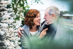 A portrait of happy senior couple in shopping center at Christmas time.
