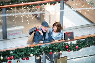 Una vista de alto ángulo de una pareja mayor con bolsas de papel en el centro comercial en Navidad.