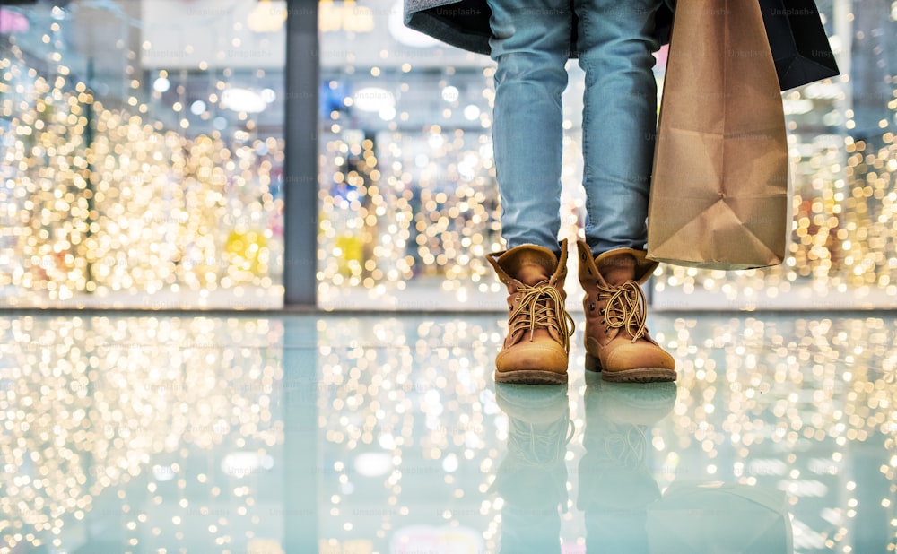 Gambe e piedi di una donna con le borse nel centro commerciale nel periodo natalizio. Copia spazio.