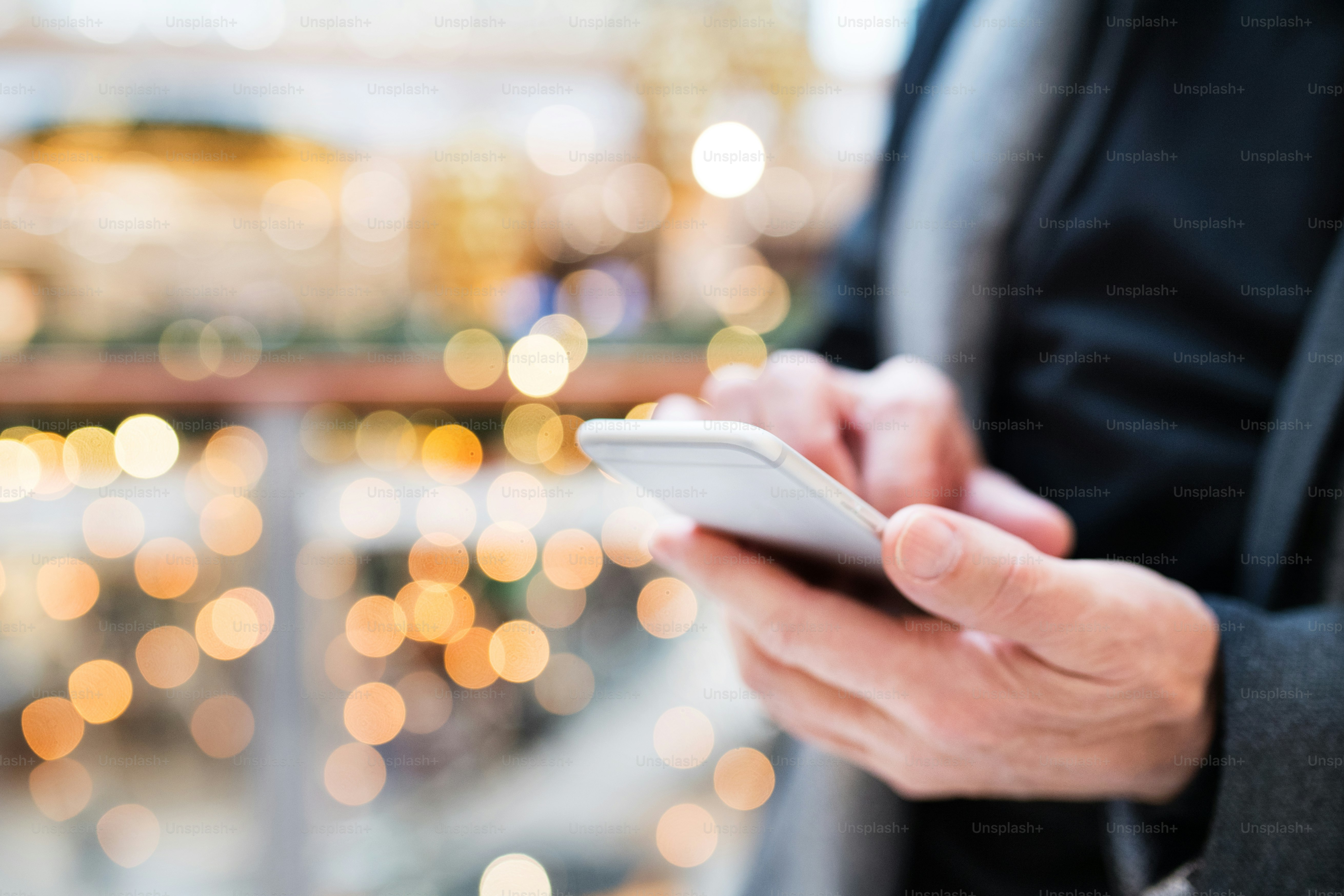 Homme âgé avec smartphone faisant des achats de Noël. Messagerie texte d’homme méconnaissable. Centre commercial au moment de Noël. Gros plan.