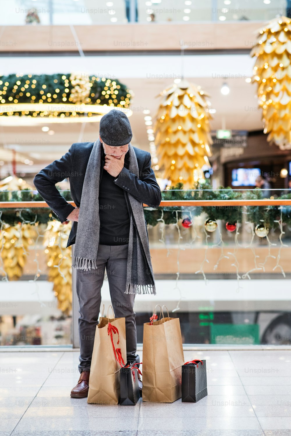 Senior man doing Christmas shopping. Shopping center at Christmas time.