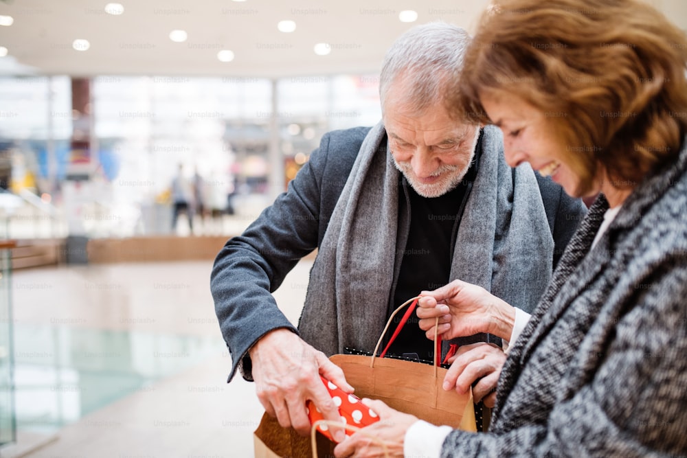 Senior couple doing Christmas shopping. Shopping center at Christmas time.