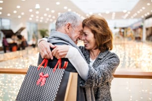 Senior couple doing Christmas shopping. Shopping center at Christmas time.