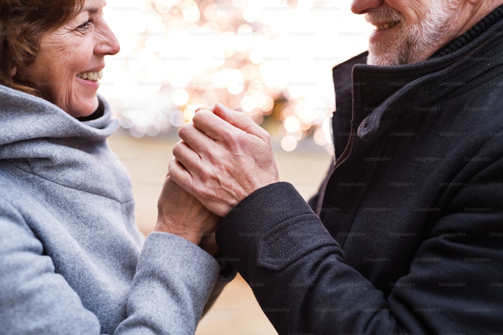 Senior couple doing Christmas shopping. Unrecognizable man and woman holding hands. Shopping center at Christmas time.