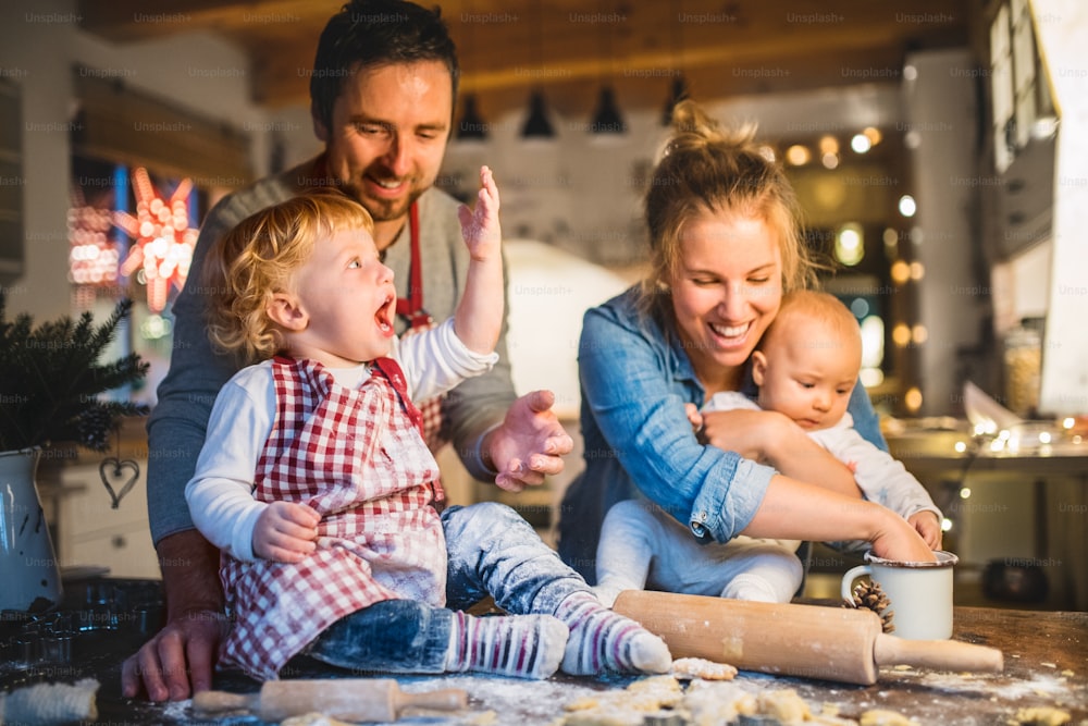 Beautiful young family making cookies at home. Father, mother. toddler boy and baby having fun.