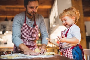 Hombre y niño pequeño haciendo galletas en casa. Padre e hijo horneando galletas navideñas de pan de jengibre.