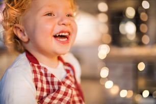 Menino feliz da criança na cozinha na época do Natal. De perto.