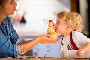 Mujer y niño pequeño haciendo galletas en casa. Madre e hijo horneando galletas navideñas de pan de jengibre.