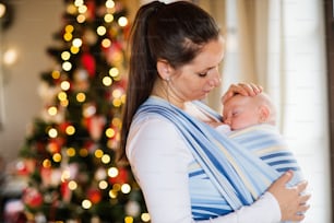 아름다운 젊은 여자가 크리스마스 시간에 아기를 감싸고 있다.