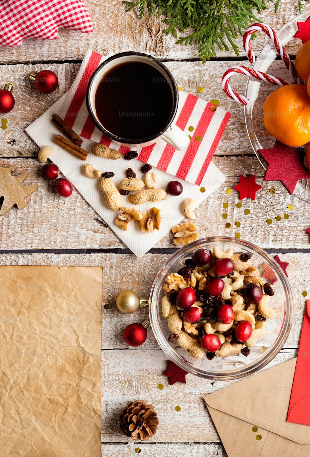 Christmas composition. Bowl with dried fruit, cranberries and nuts. Cup of coffee. Christmas decorations. Various objects laid on table. Studio shot, wooden background. Copy space.