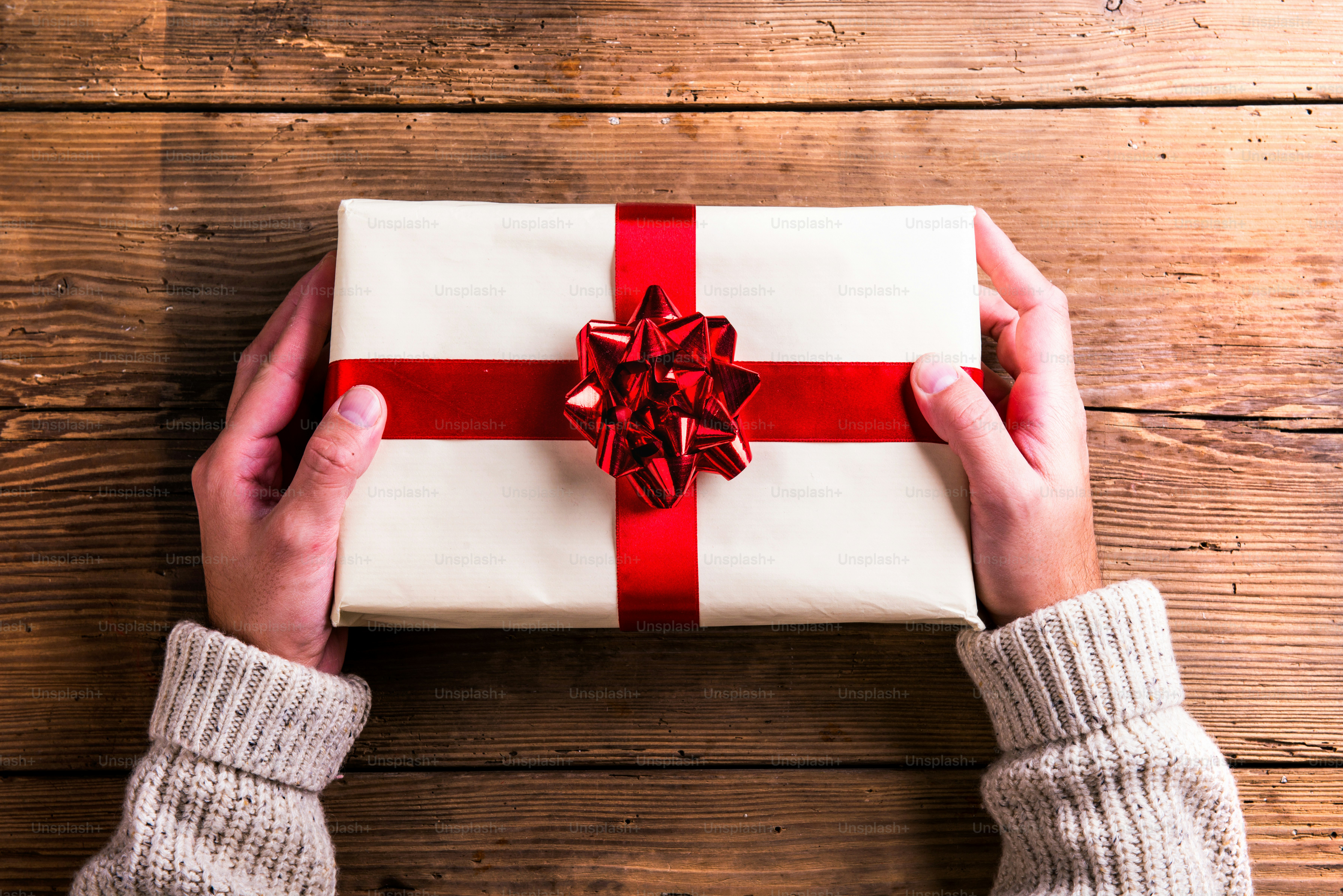 Man holding Christmas present laid on a wooden table background