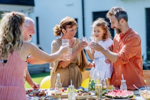Una familia de varias generaciones que celebra una fiesta en el jardín, brinda y ríe.