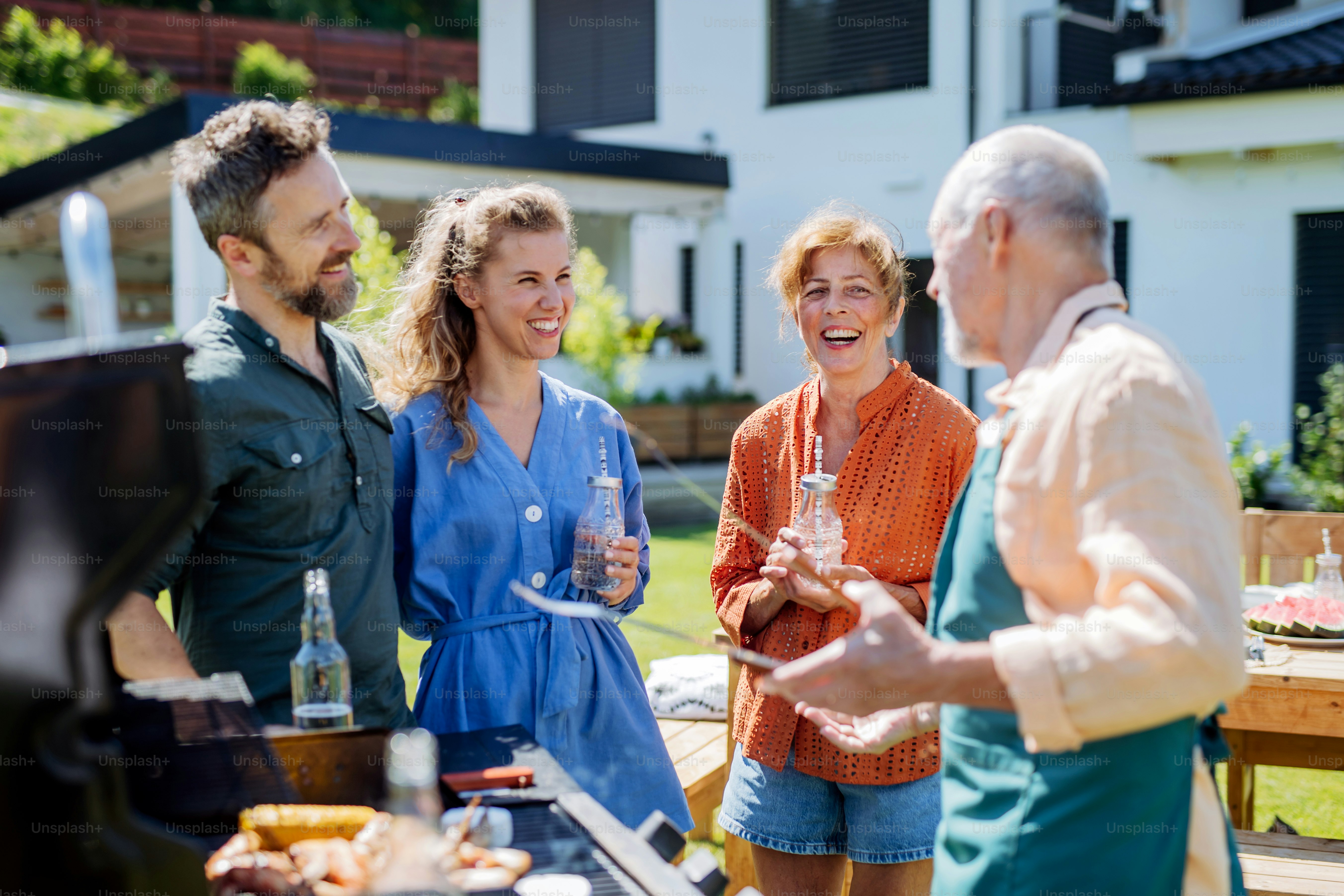 A multi generation family grilling outside on backyard in summer during ...