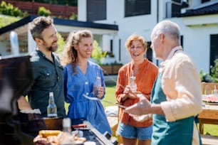 A multi generation family grilling outside on backyard in summer during garden party